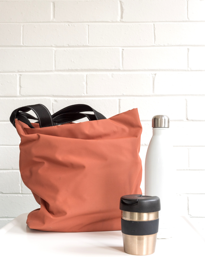 Canvas tote bag with a coffee mug tumbler and reusable water bottle.